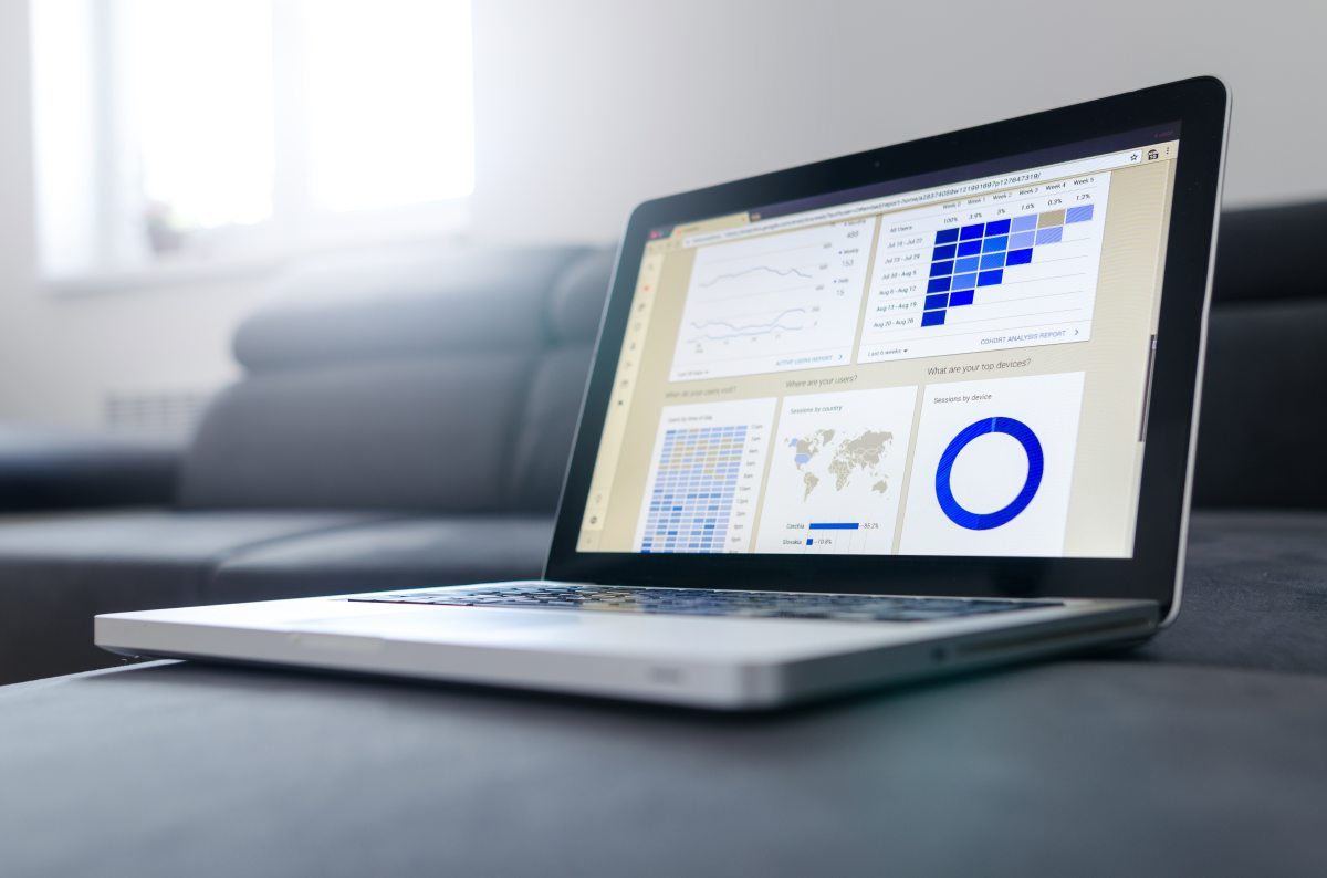 A computer screen displaying charts and data next to printed documents